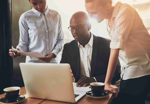 Three professionals looking at a laptop screen